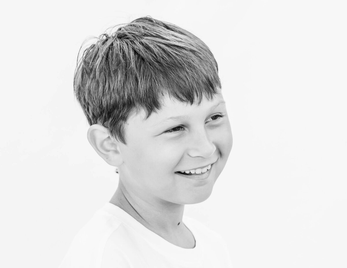5th-grade boy smiling confidently on white backdrop — S. Reed Photography fine art school portrait