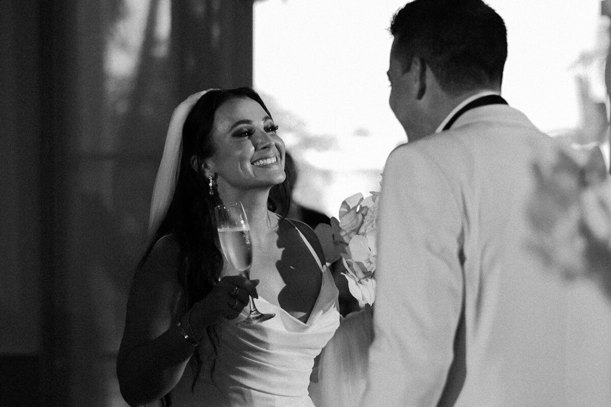 The bride joyfully smiles while holding a champagne flute during the wedding reception in Miami, photographed by Claudia Amalia Photography.