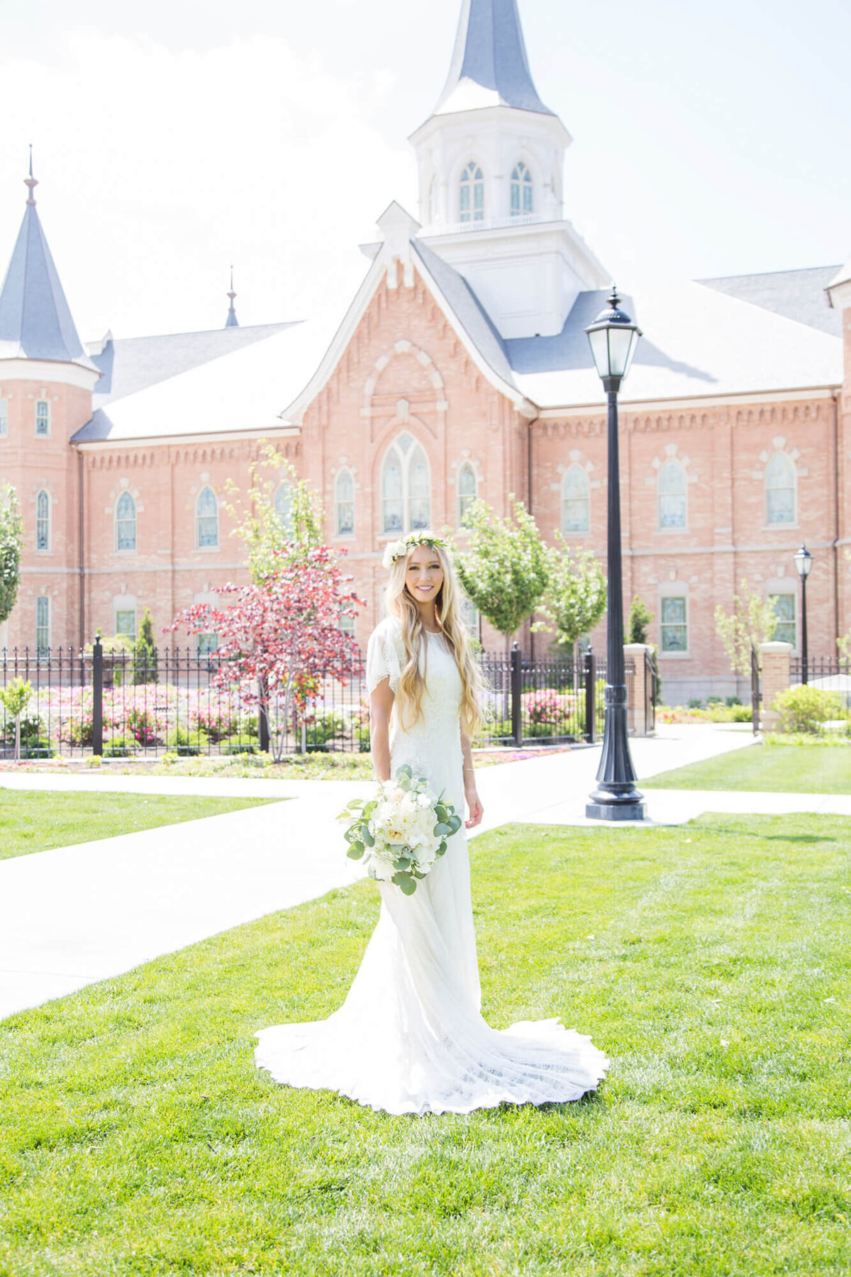 blonde bride at wearing a wedding dress standing in front of a brick lds temple