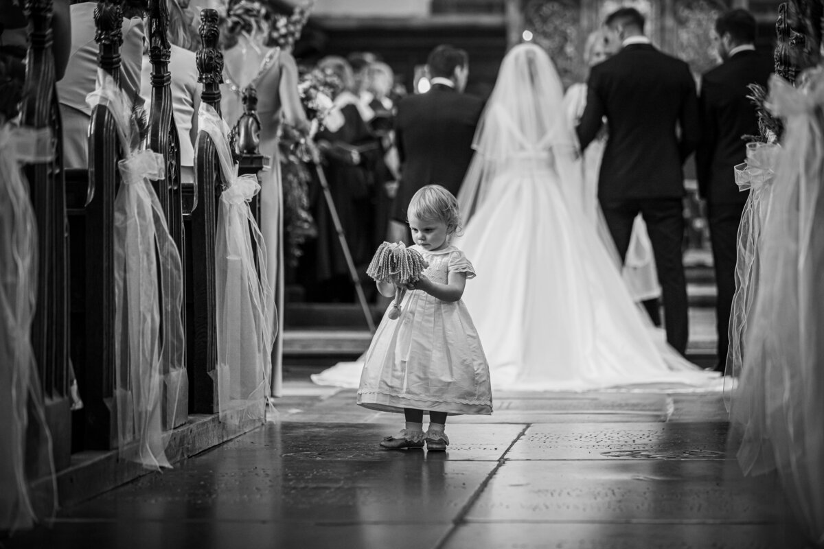 The flower girl stood in the aisle with her dolly during the wedding ceremony
