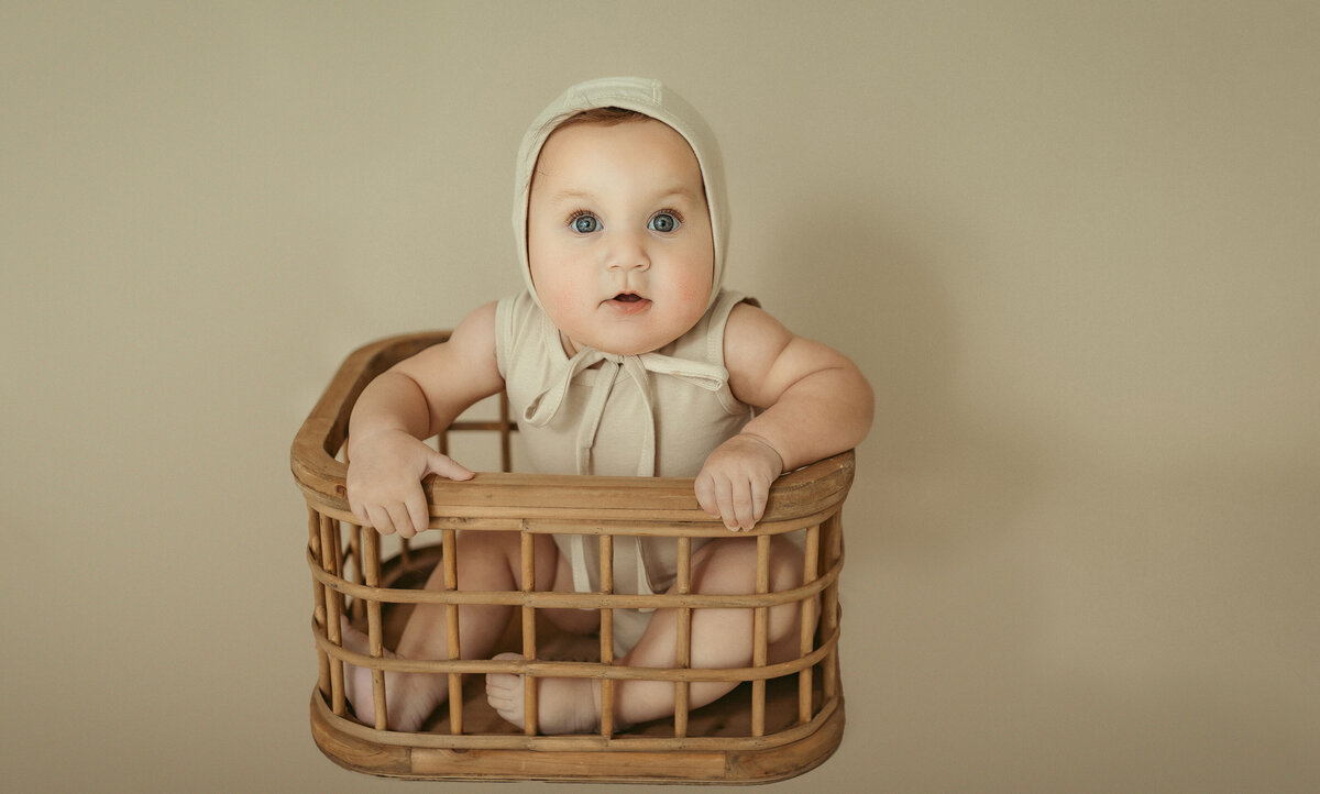 milestone photo for baby girl. The baby is wearing a neutral outfit that matches the background color