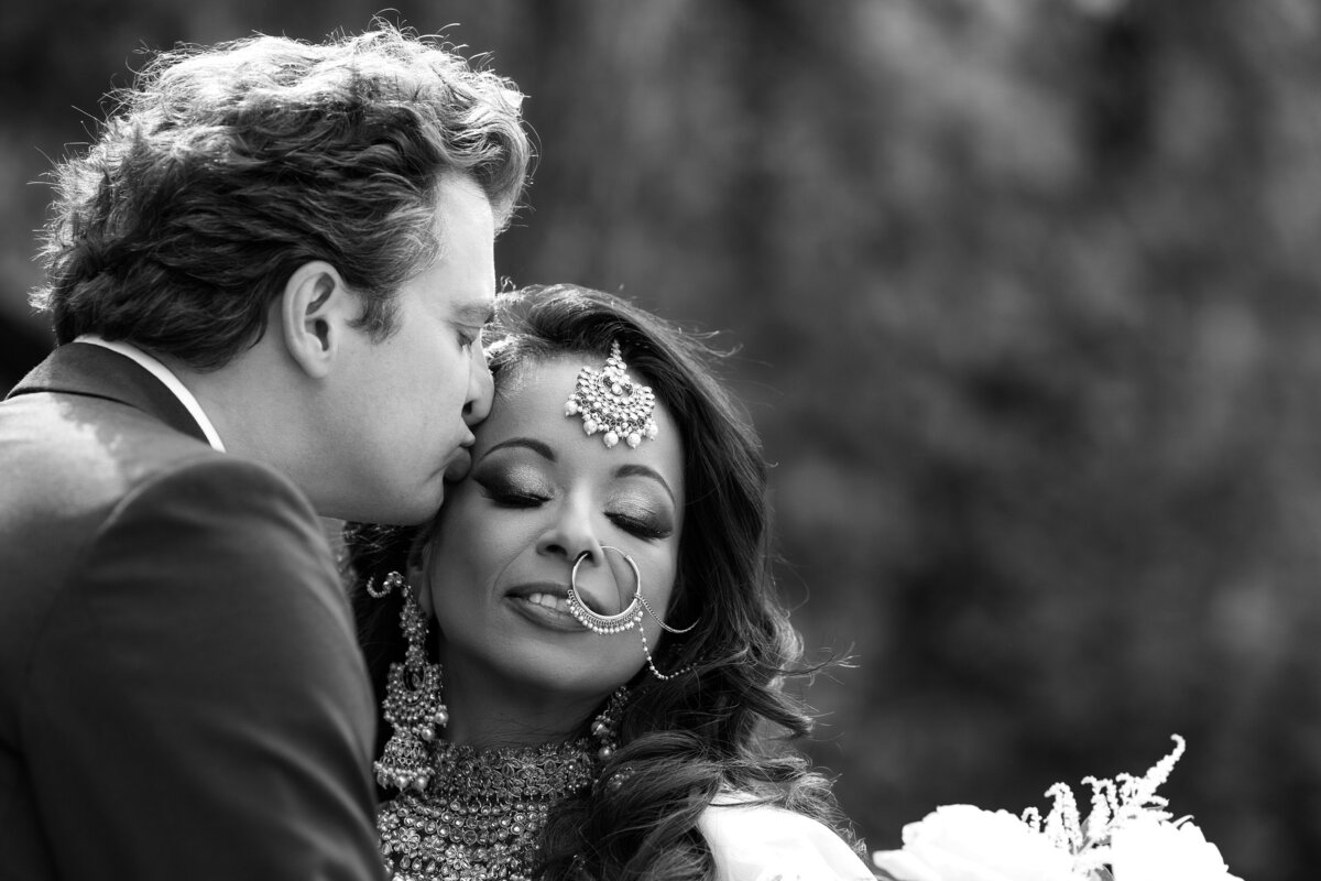 Groom kisses his bride on the temple