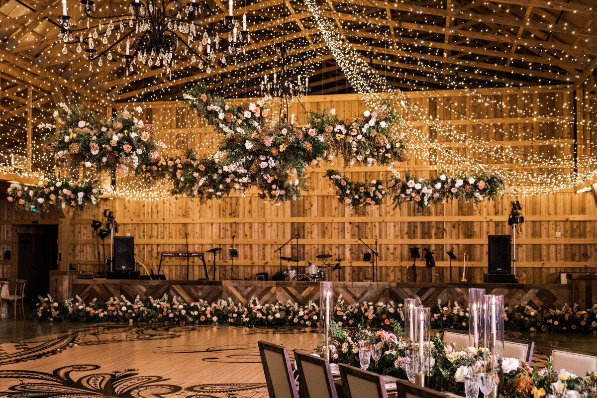 Gorgeous autumnal floral clouds hang over the dance floor, including terra cotta, rose gold, toffee, blush, and neutral florals. These clouds feature lush garden roses, ranunculus, lisianthus, and privet berries. Designed by Rosemary and Finch in Nashville, TN.