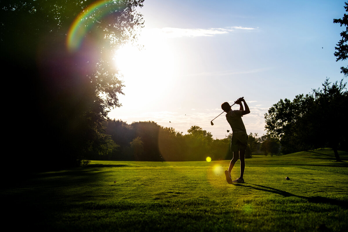 golf silhouette of high school senior swinging club at sunset