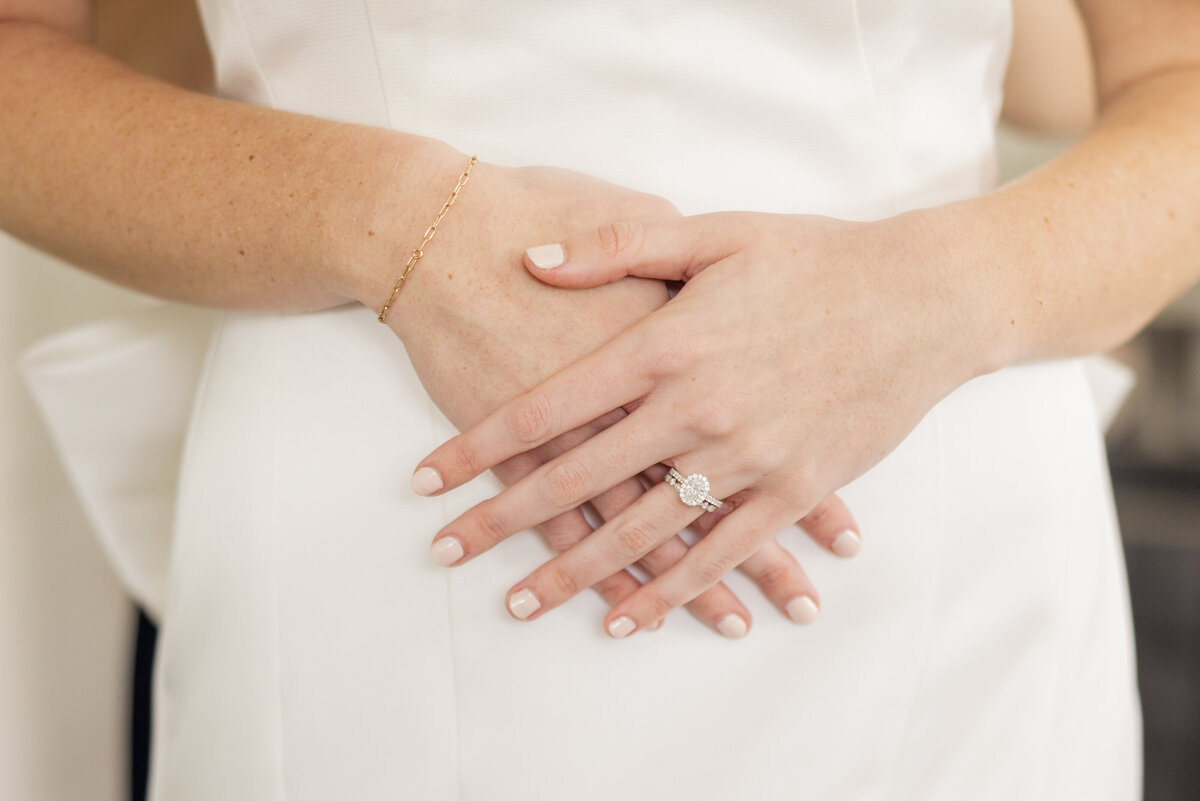 Close up of brides engagement ring while she's being fastened into her gown. 