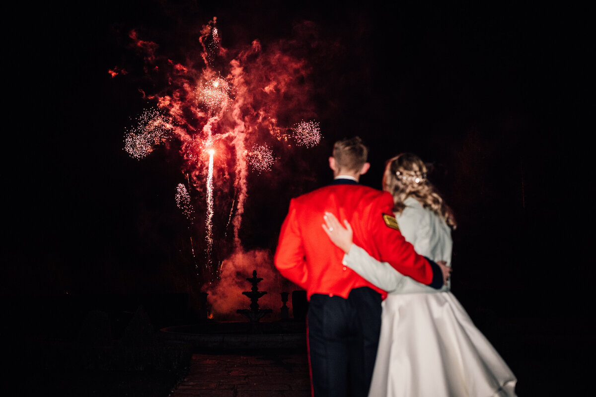Fairytale winter wedding couple watching red fireworks at night