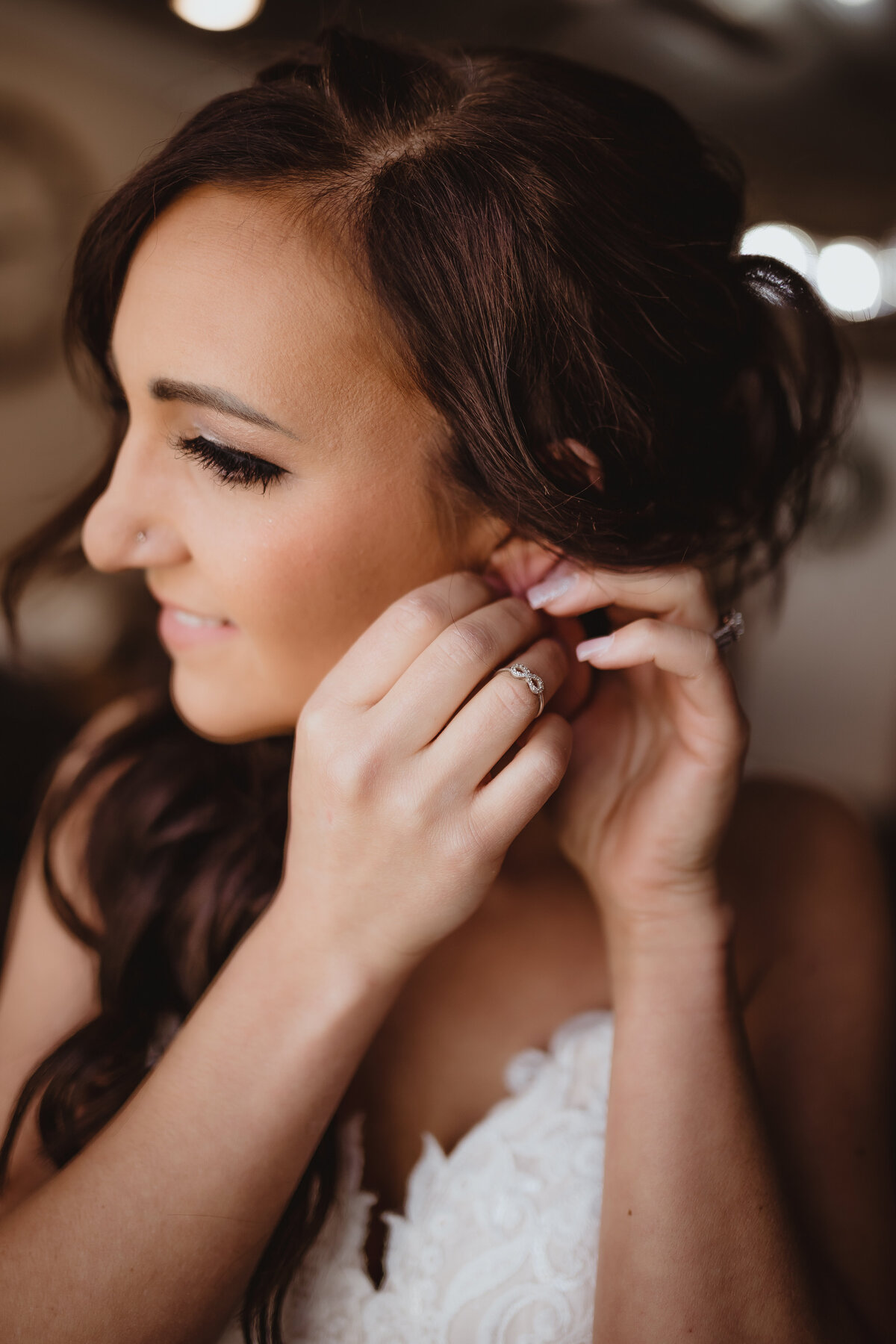 BRIDE PUTTING ON EARRINGS GETTING READY FOR HER WEDDING