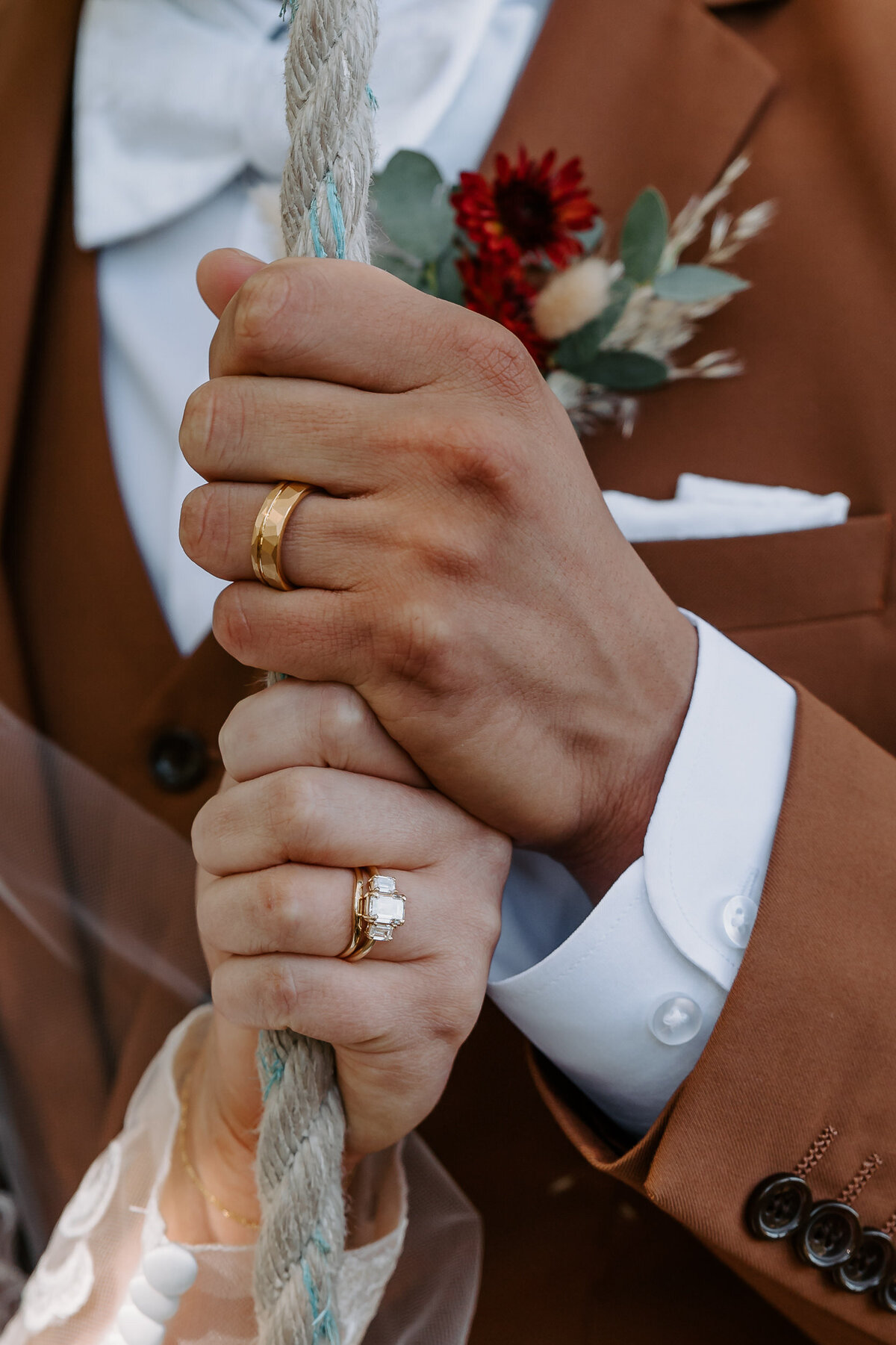 Two hands holding a rope showing off wedding rings