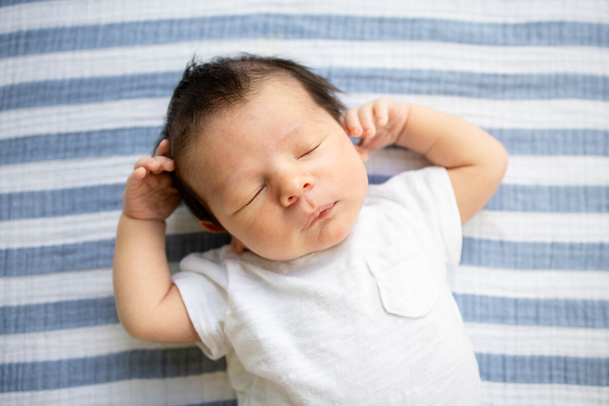 Baby boy sleeping on blue and white stripped blanket