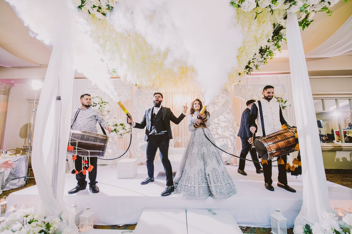 indian bride and groom spraying co2 cannon guns on stage during the wedding reception