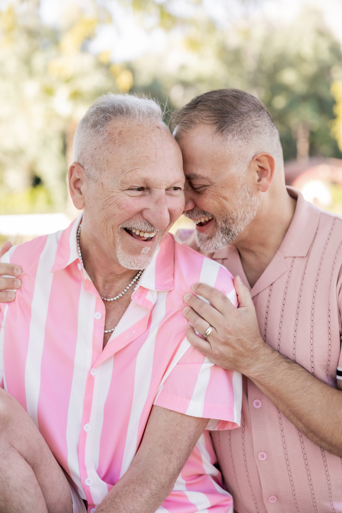 Couple seated side-by-side, holding hands in a relaxed moment of love and warmth, framed by desert greenery.