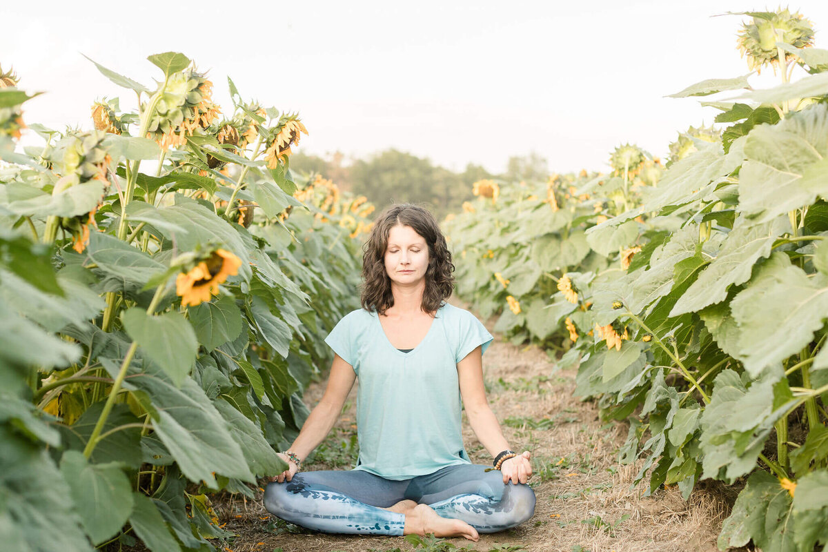 Rachel Cline meditating in a sunflower field