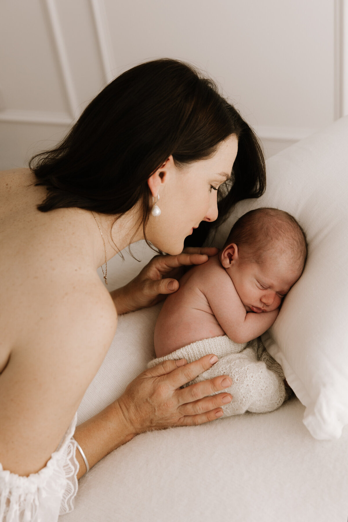 Mother gently watching over her sleeping newborn baby during a soft and intimate newborn photography session in Southwest Sydney.