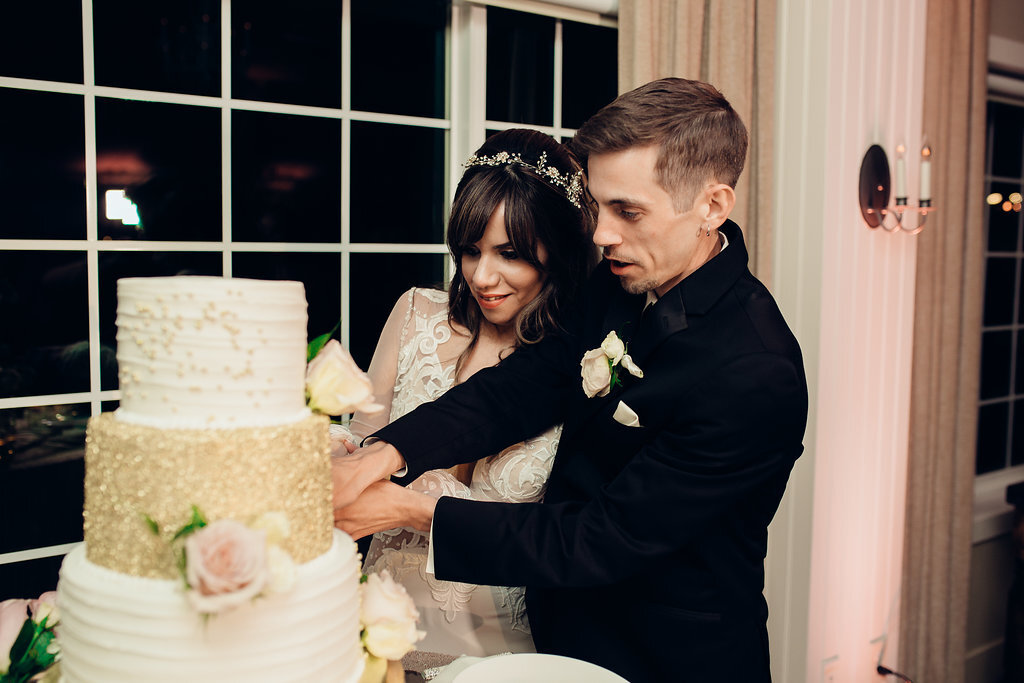 Wedding Photograph Of Bride In White Dress And Groom In Black Suit Cutting The Cake Los Angeles