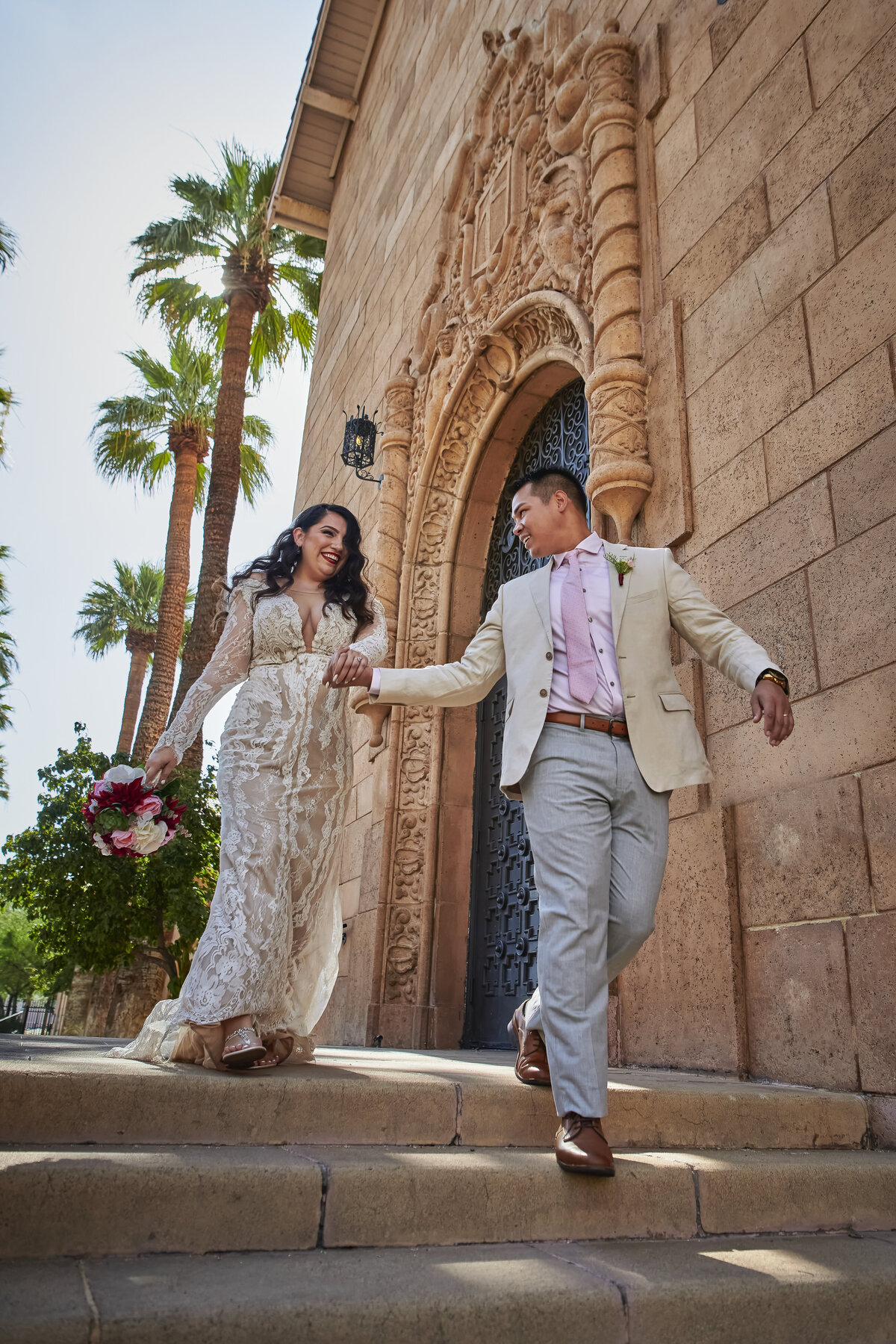 Groom escorts his bride down stone stairs