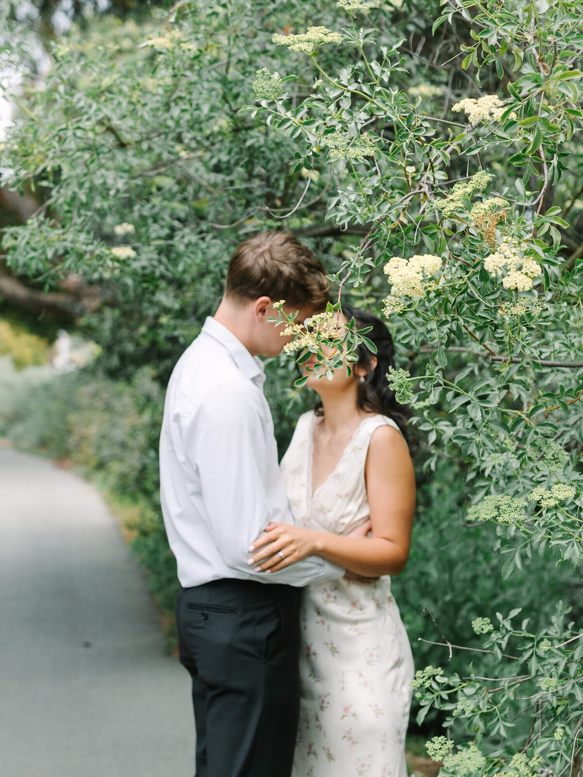 engagement photo of bride and groom standing behind a tree at san diego botanical garden