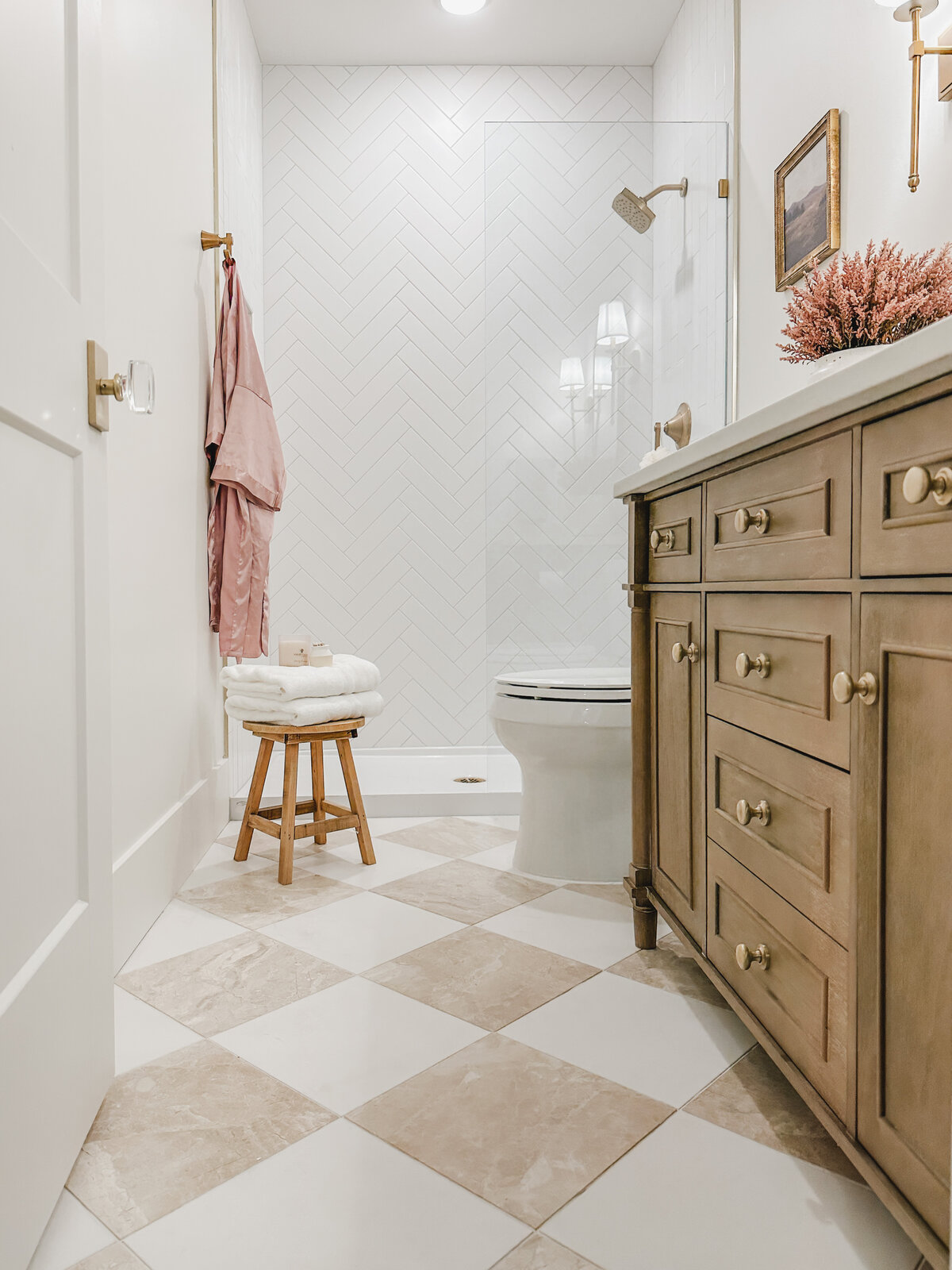 The guest bathroom features a show-stopping neutral checkerboard floor done with faux marble tile