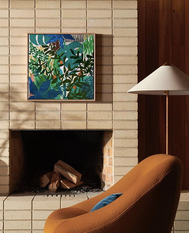 Square green and blue artwork above light brick fireplace with modern armchair styled by residential interior design expert Lisa Hunter Interiors.