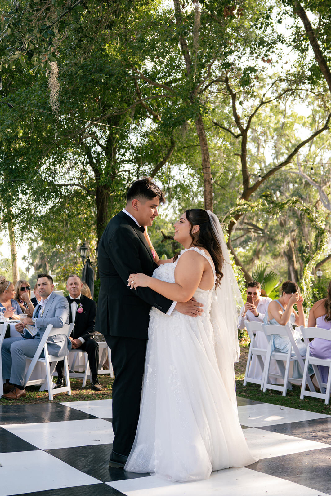 Bride and groom standing beneath a large oak tree having their first dance at Uliana Estate, a romantic Lakeland Florida wedding venue.