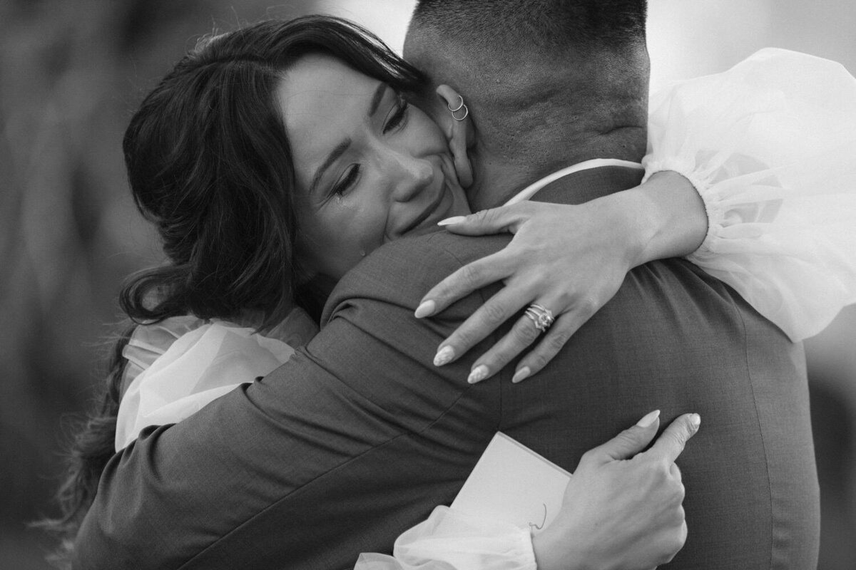 A bride who just got married sheds a tear as she hugs her husband