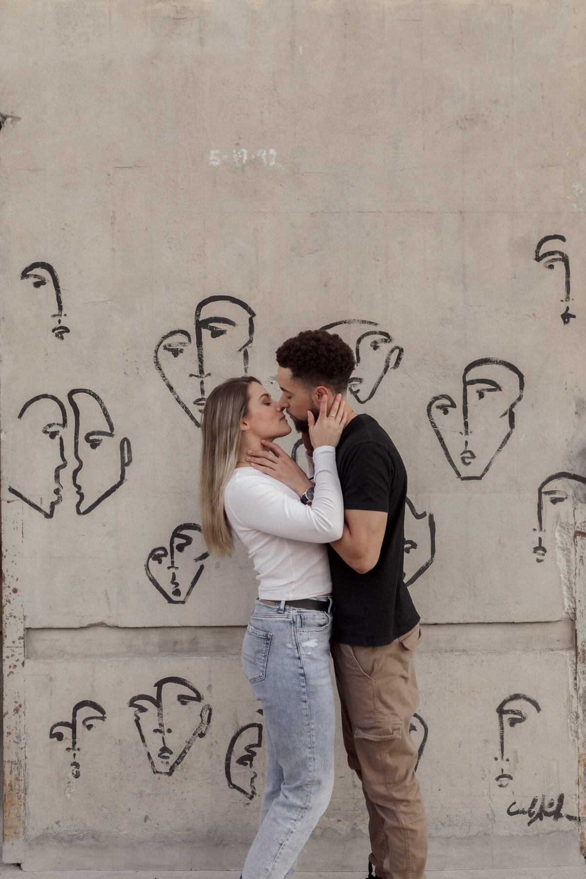 couple kissing in front of concrete wall