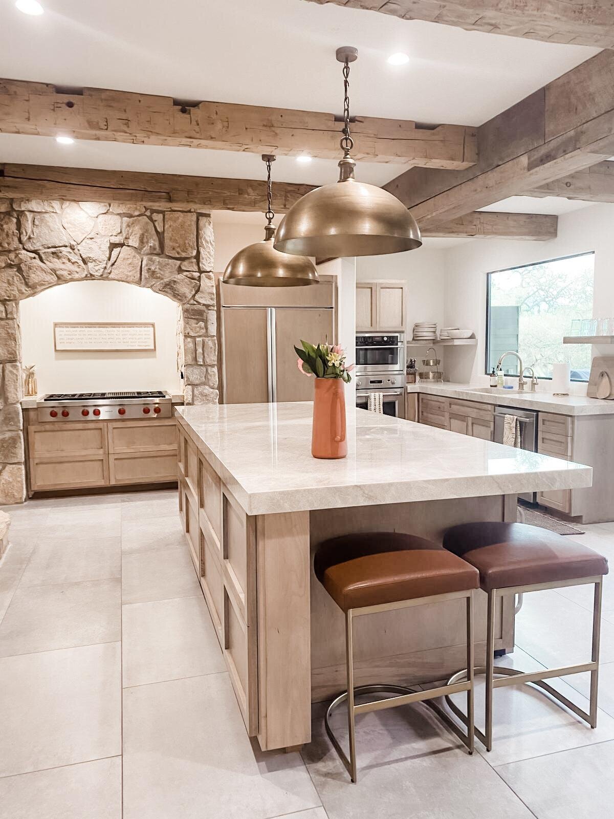 Kitchen island in a wooden and golden colour palette kitchen with a large stove