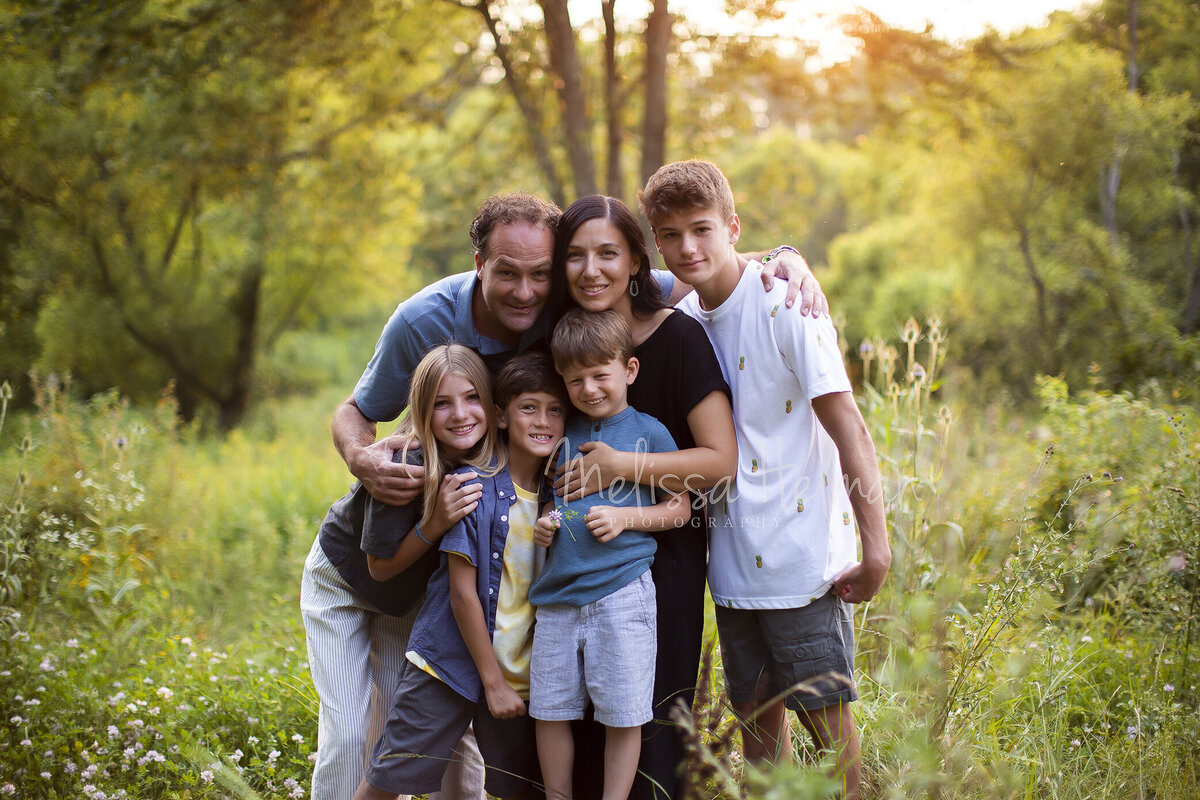 Family hugs each other for their family session  in Greensburg field.