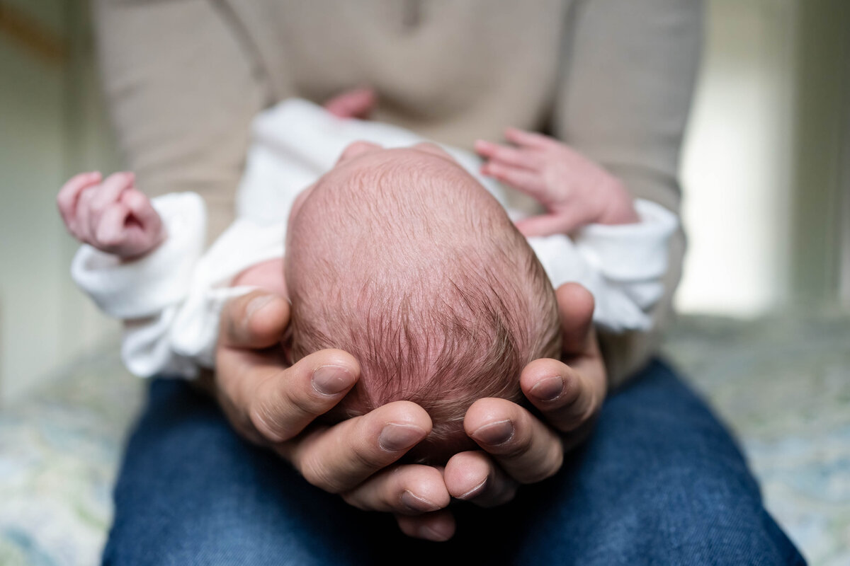 Baby in dad's hands during in-home newborn session