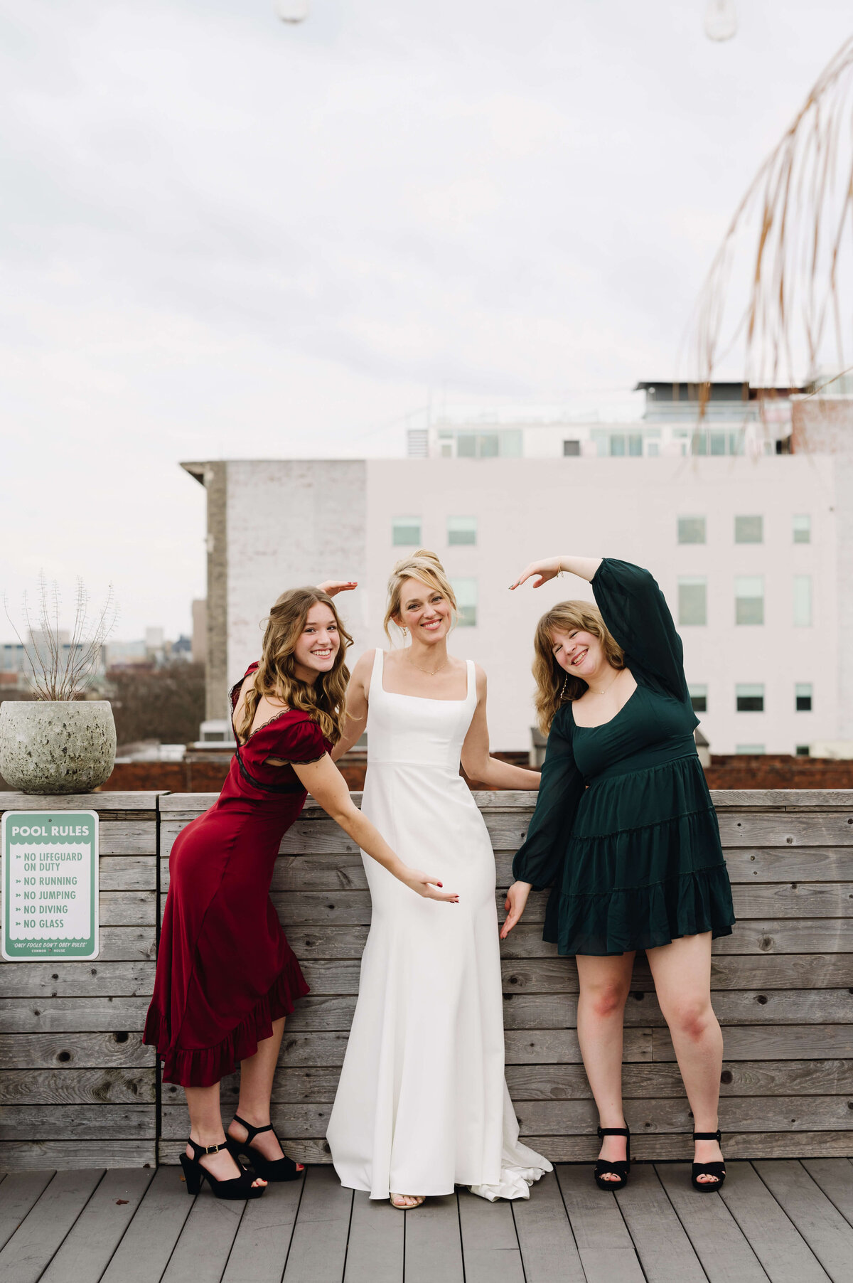 winter wedding with bride surrounded by her bridesmaids as they make hearts with their hands surrounding her captured by Richmond wedding photographer