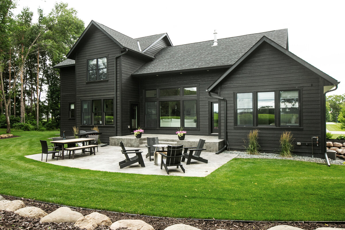 Exterior view of custom home in Otsego, Minnesota with black siding, large patio and windows built by Cornerstone Custom Builds