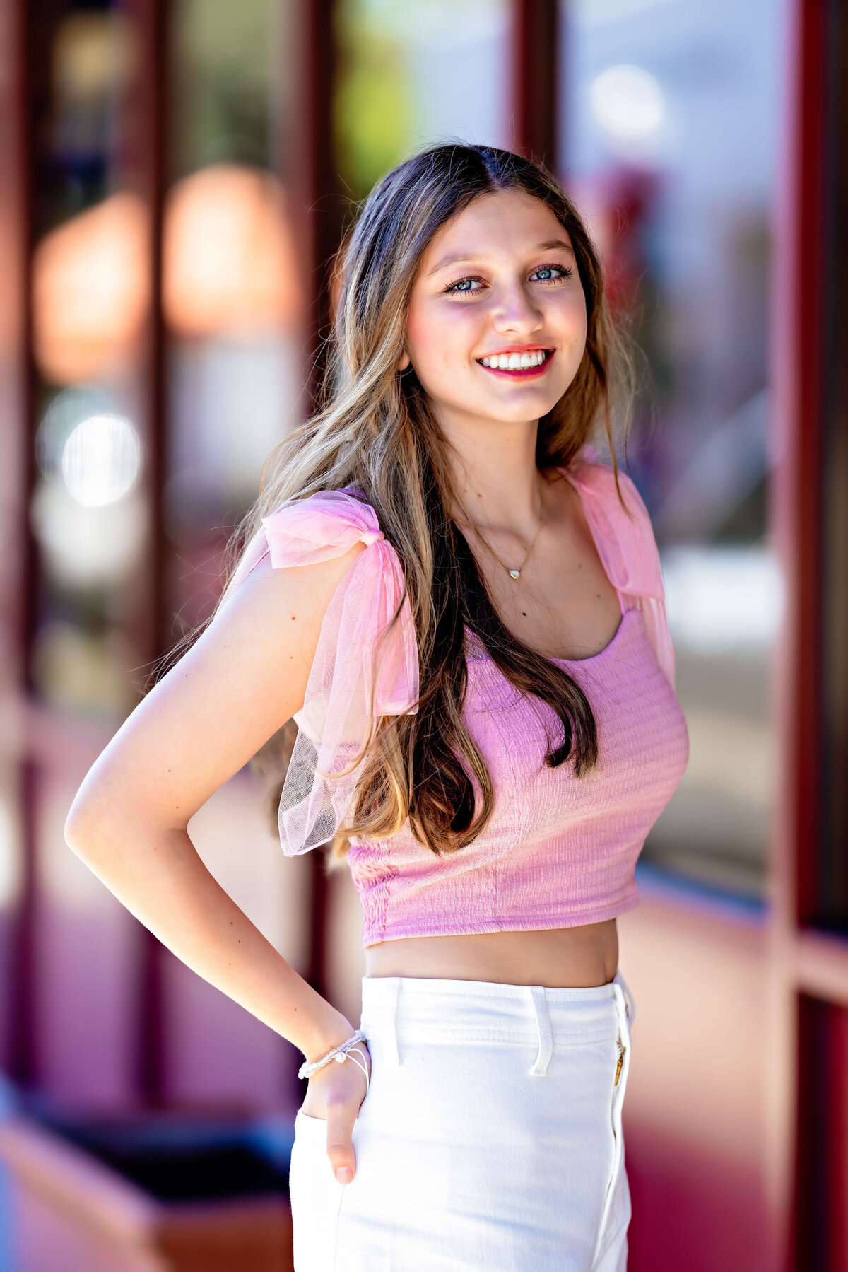 Smiling high school senior in pink top during city-inspired session in Lake Nona, Florida