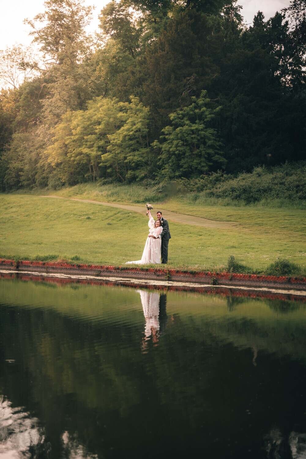 Bride and Groom embrace next to lake