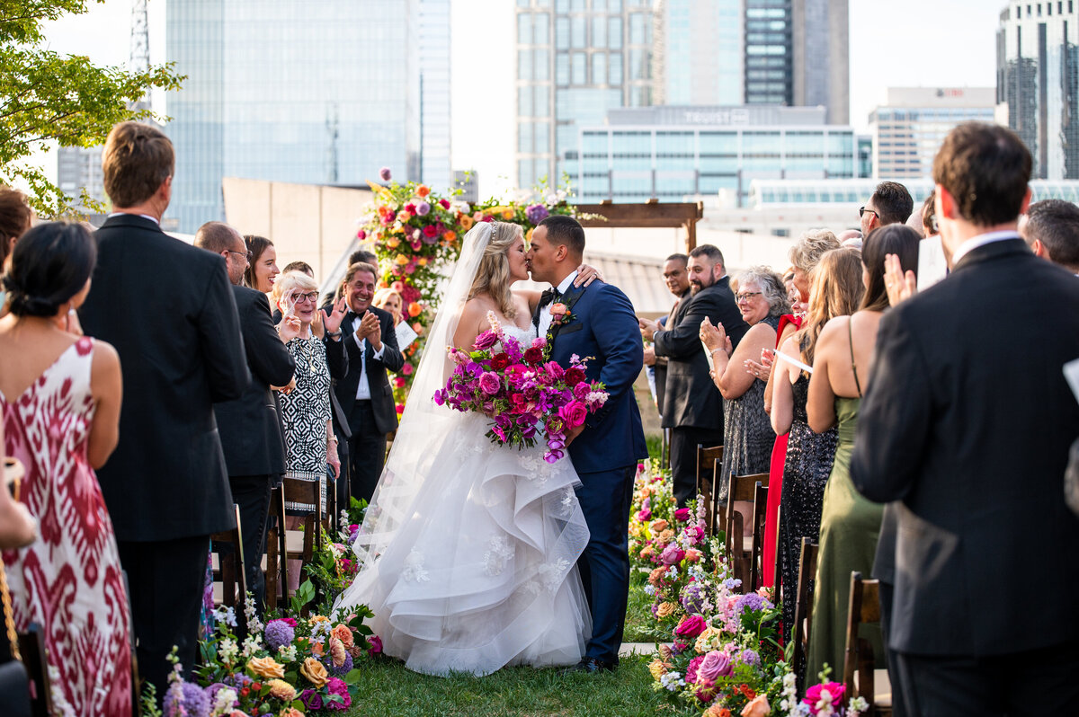 Eye-catching bright pink and fuchsia bridal bouquet composed of phalaenopsis and makara orchids, peonies, garden roses, and ranunculus. Design by Rosemary and Finch in Nashville, TN.