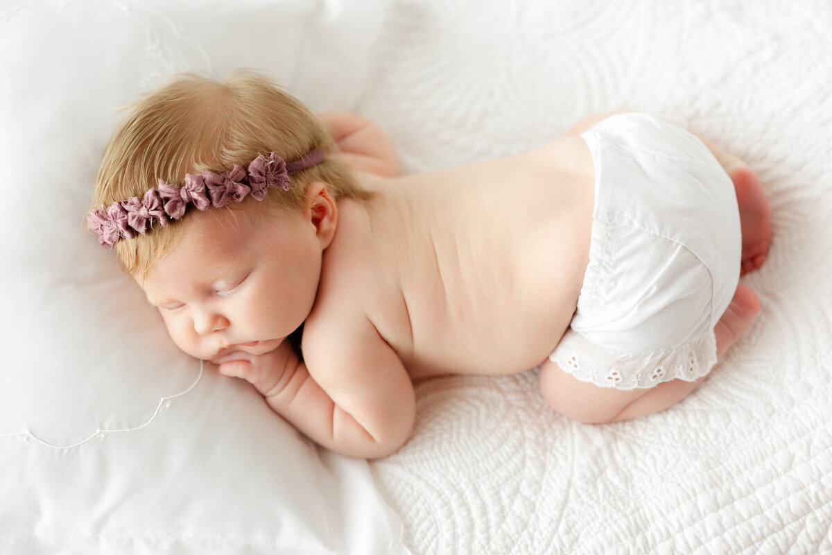 An overhead view of a little baby with white bloomers and purple headband at a studio in Savannah, Ga