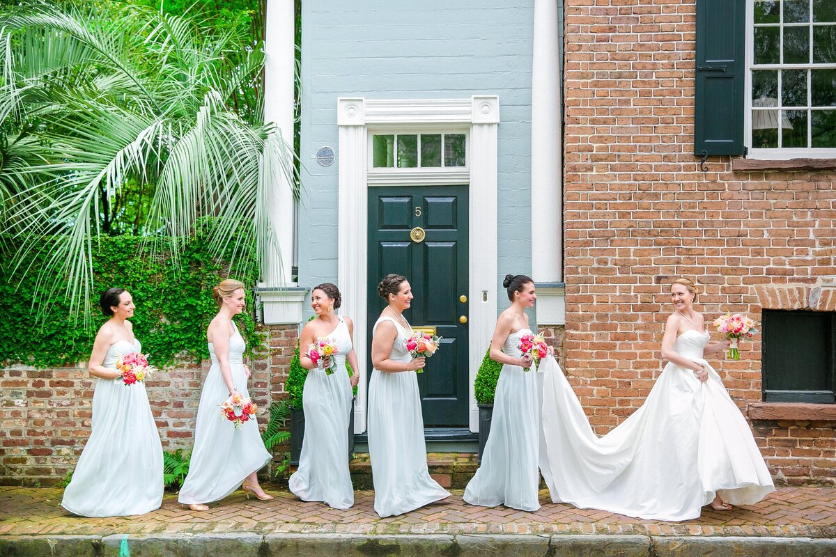 bridesmaids help bride walk down the street in her dress charleston sc