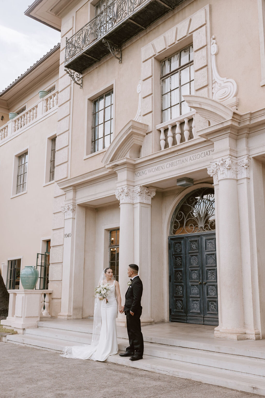 Bride and groom in front of the Cafe Julia Hawaii building with european architecture and a large black door