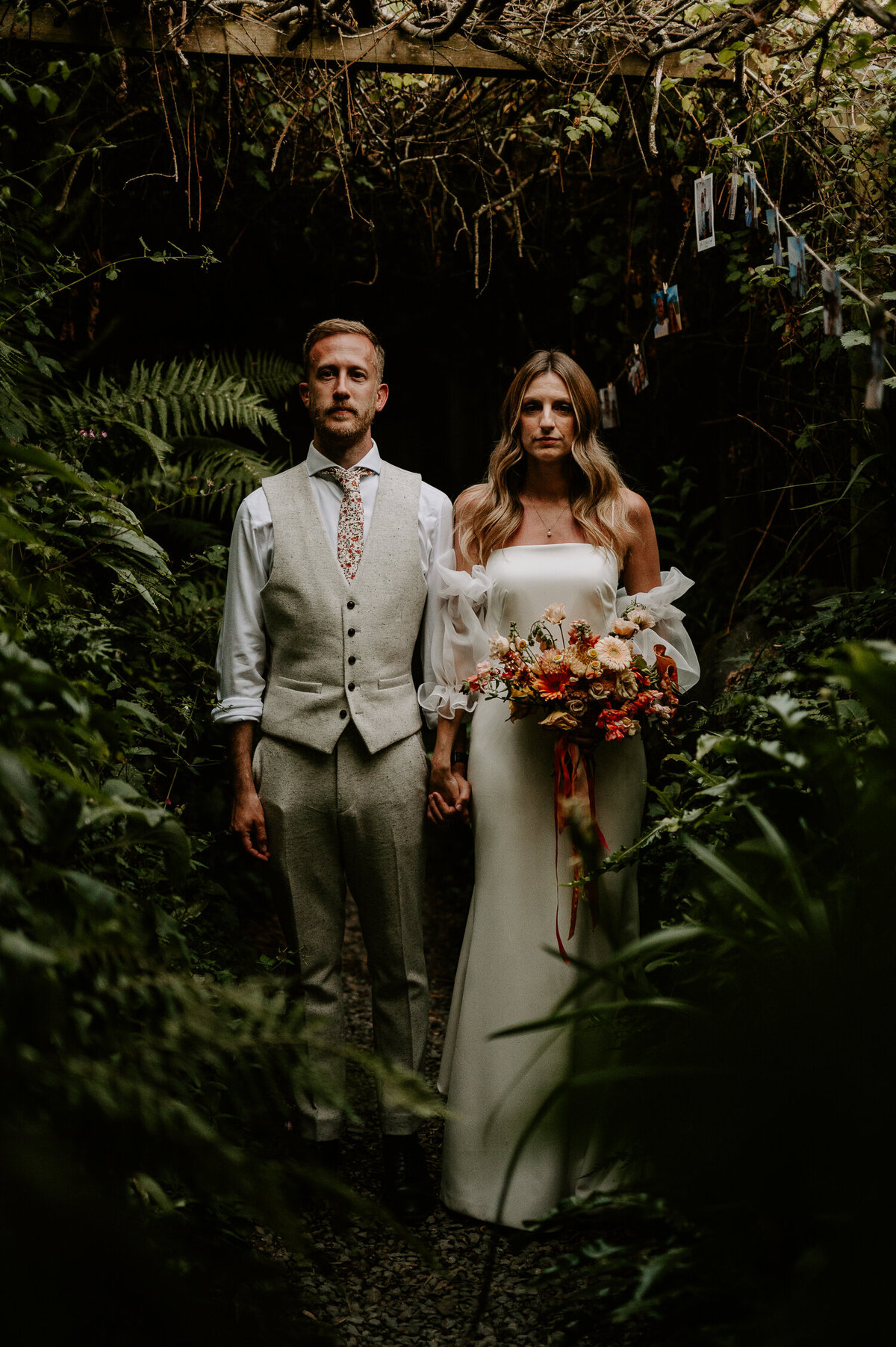 A bride and groom stand in a small corridor of plants at ANRAN at Tidwell Farm. It really gives off the jungle wedding vibe.