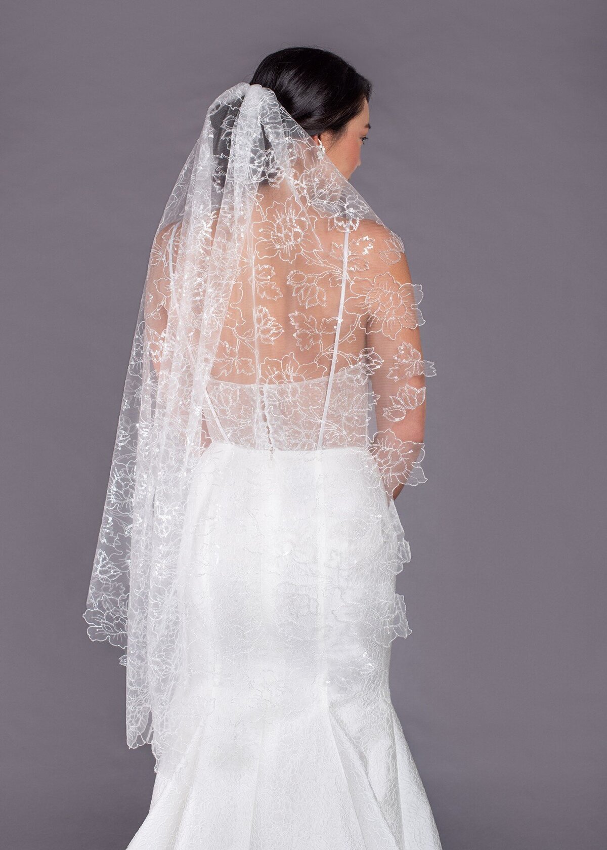The organic cut edge of the Lilies Veil follows the pattern of the sequin and flower embroidered pattern of the tulle. The top edge is gathered onto a comb for wearing.