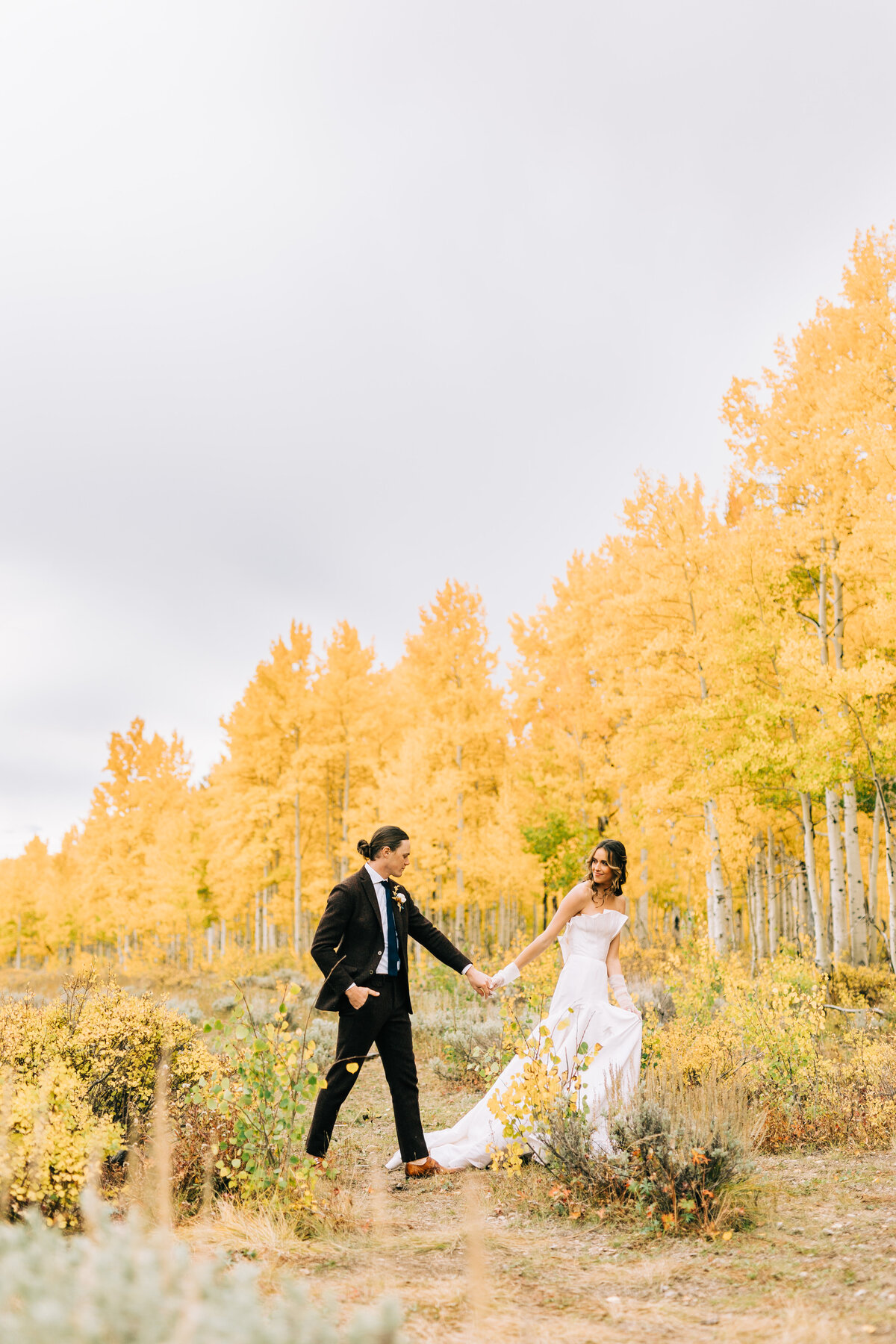bride and groom walk hand in hand among fall foliage by winx photo tennessee wedding photographer