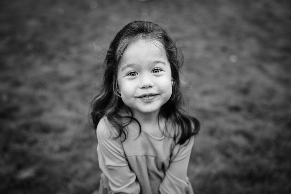 A child smiles in a black and white photo.