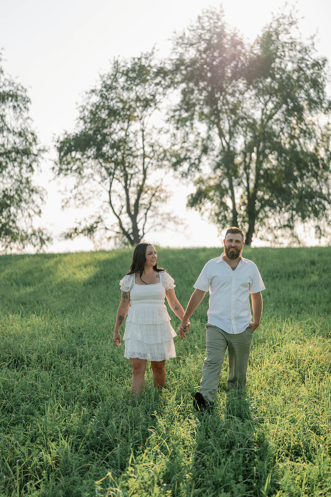 Kali and Joe walking through a grassy field at sunset on private property outside Detroit.