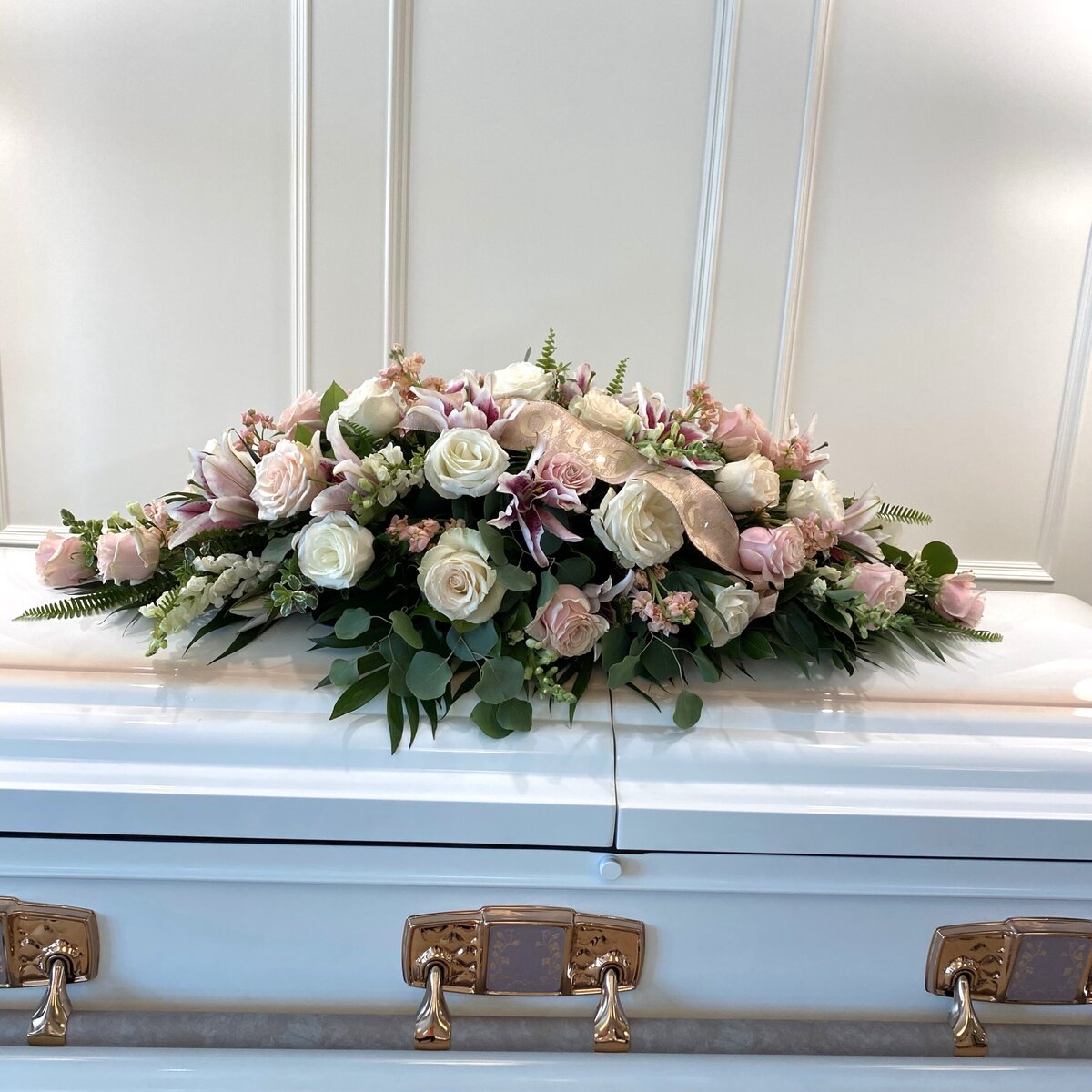 pink and white funeral casket spray with beloved mother on the ribbon