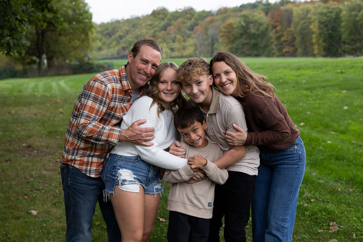 Familyholdingeachotherinafieldsmilingatcamera.
