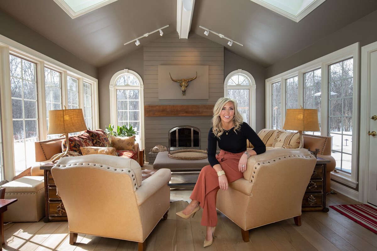 Woman in black top and orange pants sitting in a cozy living room