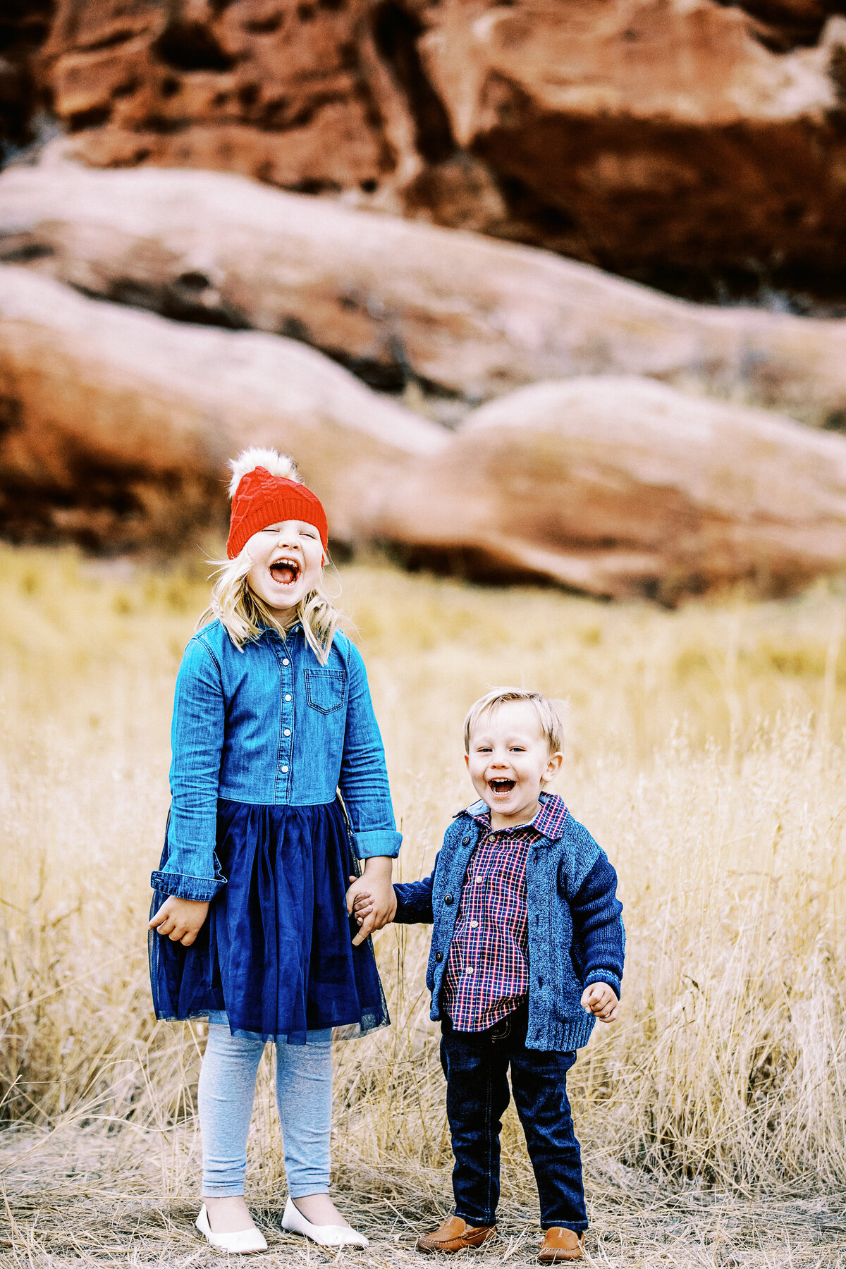 brother and sister hold hands and laugh