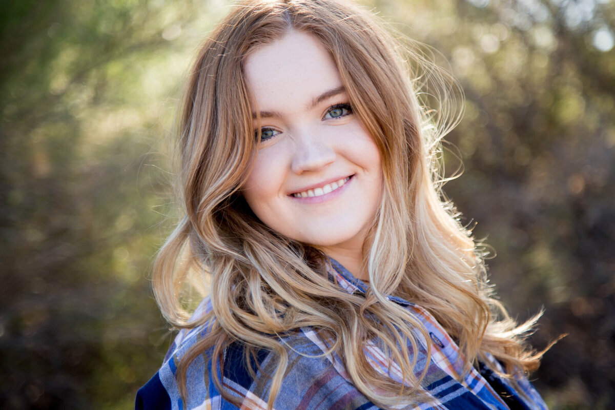 Beautifully backlit senior girl smiling for a portrait with las vegas milestone photographer Jessica Bowles