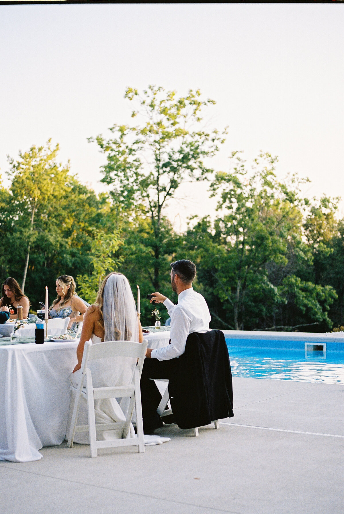 bride and groom sitting poolside at reception