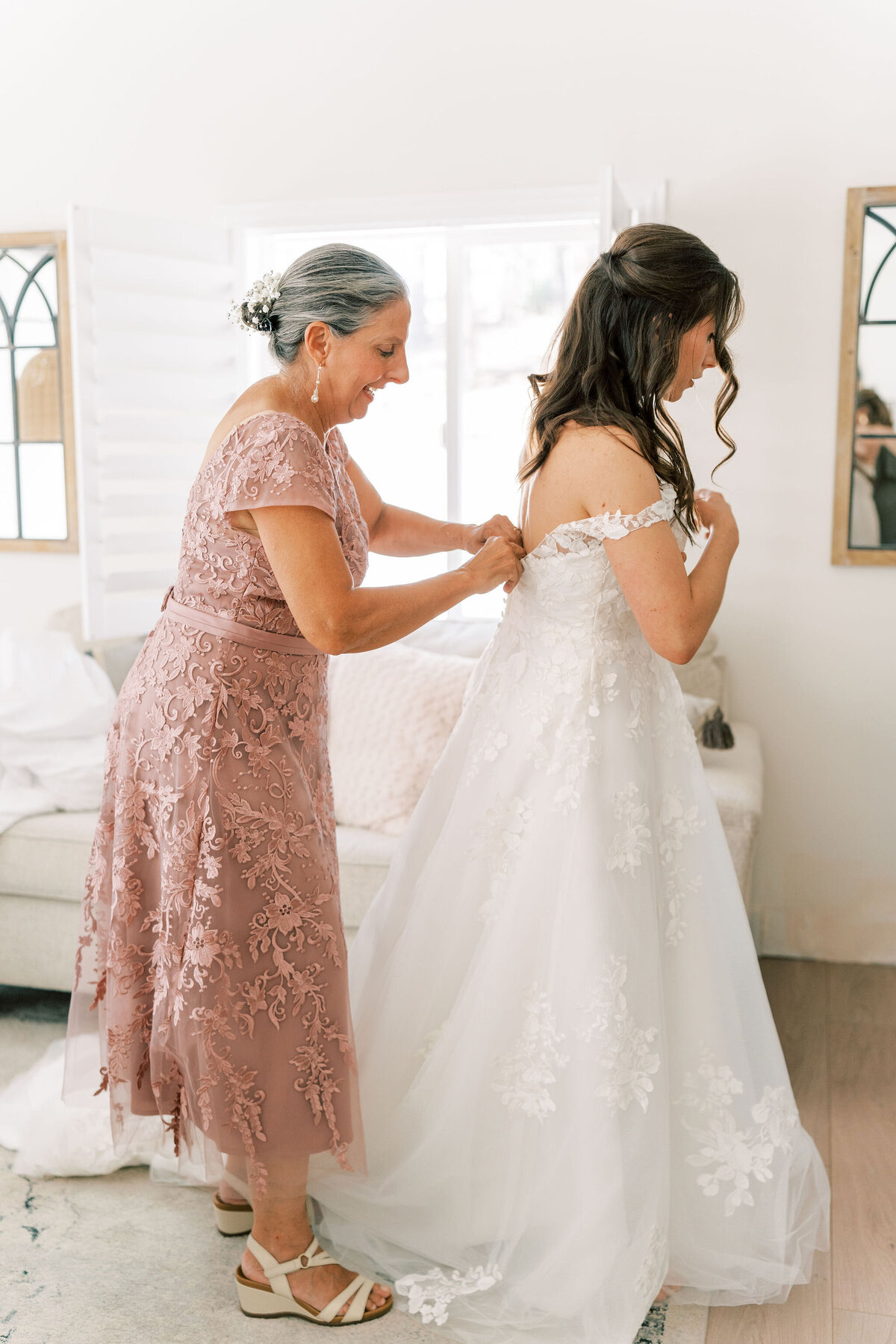 mother adjusts daughters wedding gown
