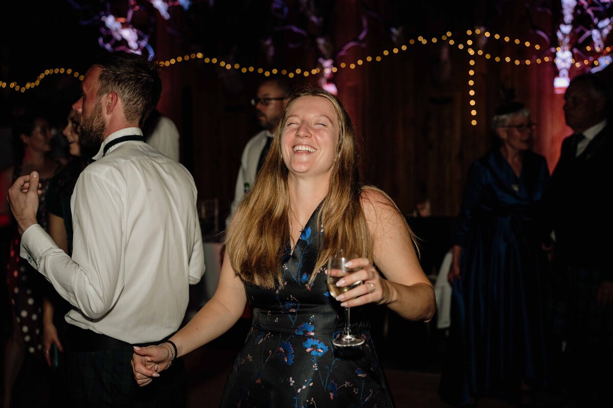 A guest dances to ceilidh music while holding drinks.