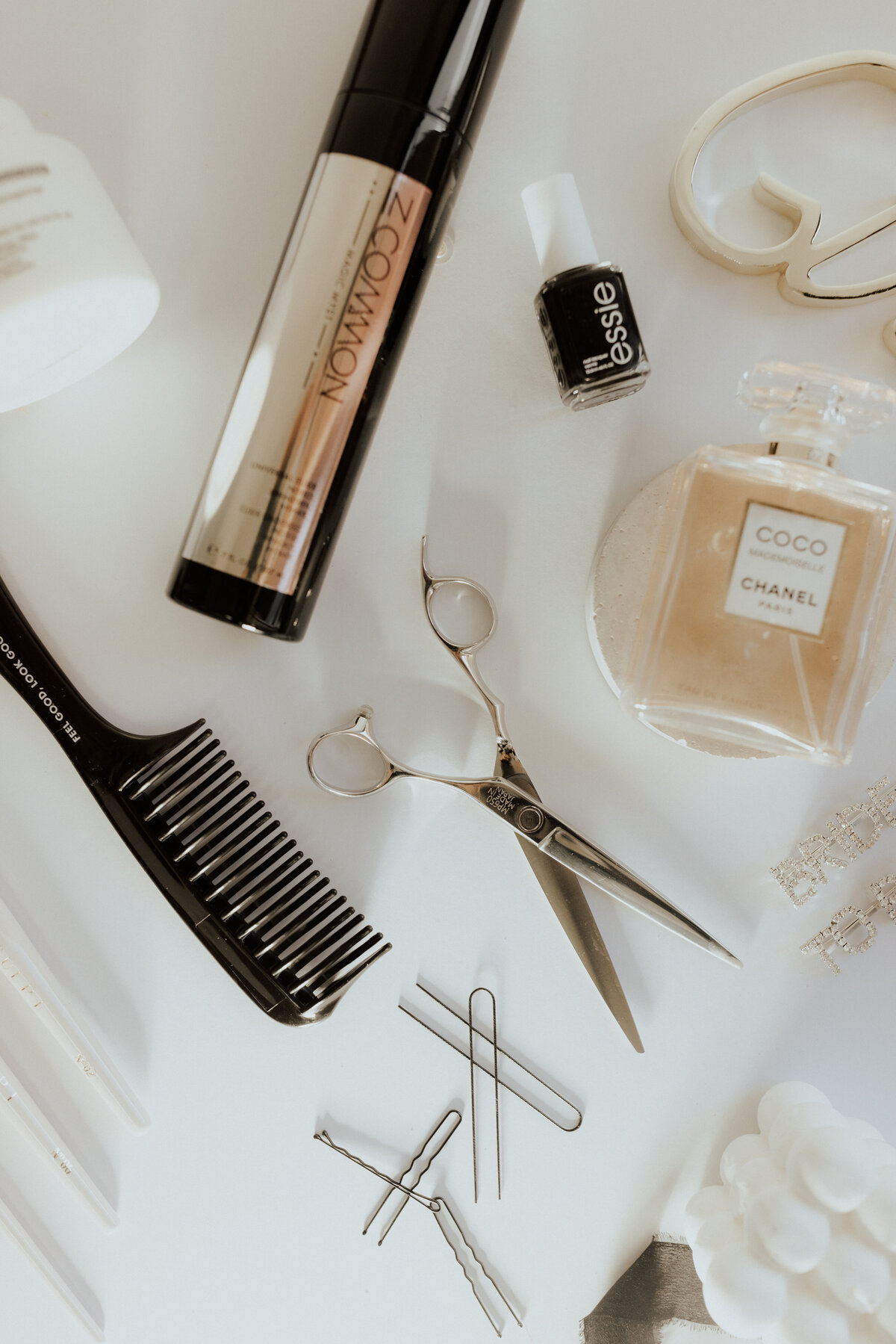 A bright, clean flat lay showcasing luxury beauty essentials including scissors, combs, Essie nail polish, and Coco Chanel perfume. Perfect for salon branding and high-end editorial use. Captured by Dani Lacey in Greenville, SC